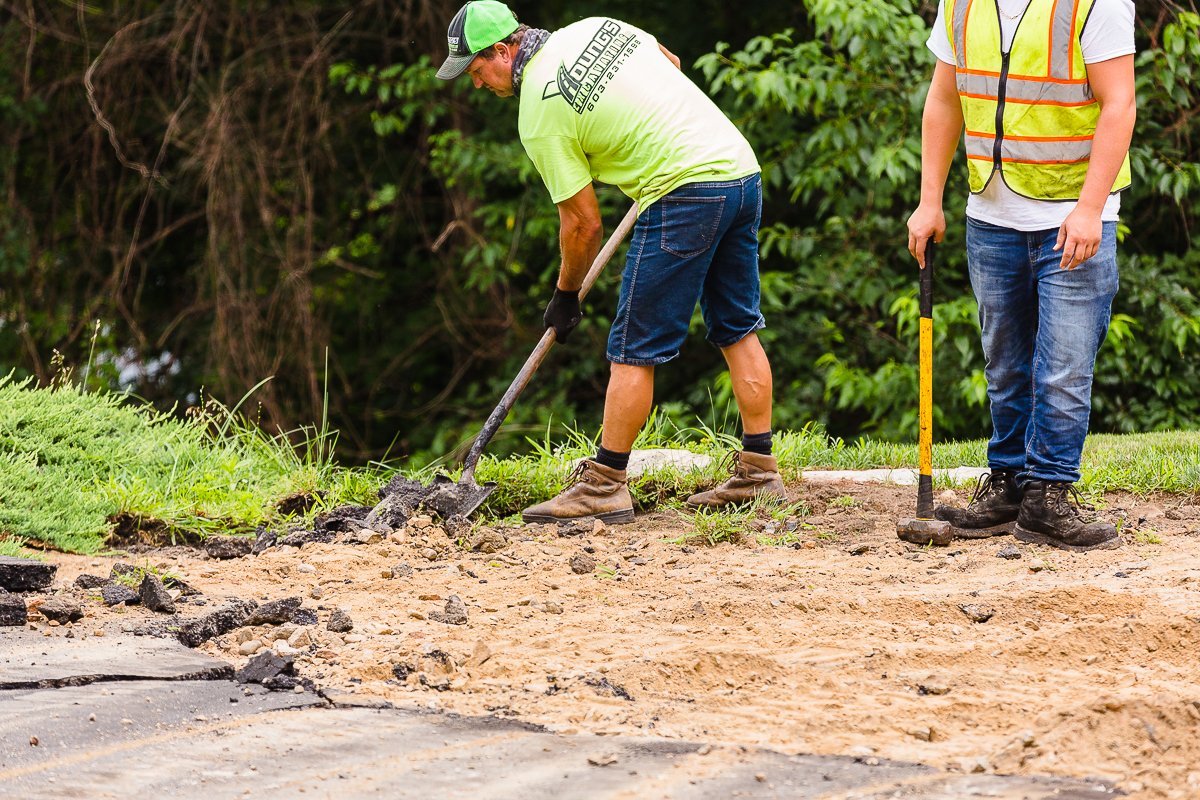 Young's Excavating & Paving crew members break out old pavement and prepare the base during a New Hampshire driveway project.